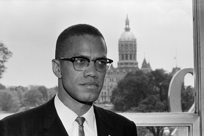 Malcolm X in his Black Suit and Tie, Rubbing his Head